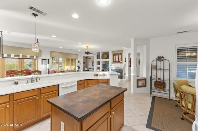 kitchen featuring white dishwasher, a center island, sink, light tile patterned floors, and pendant lighting