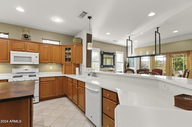 kitchen featuring kitchen peninsula, sink, light tile patterned flooring, pendant lighting, and white appliances