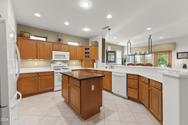 kitchen featuring kitchen peninsula, white appliances, light tile patterned floors, and hanging light fixtures