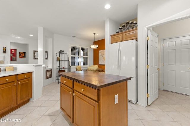 kitchen with white fridge, a kitchen island, decorative light fixtures, light tile patterned floors, and an inviting chandelier