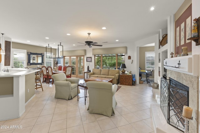 tiled living room with a wealth of natural light, ceiling fan, and a premium fireplace