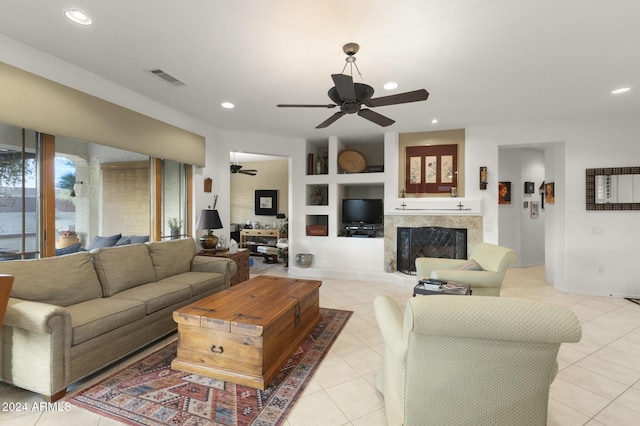 living room with built in shelves, light tile patterned flooring, and ceiling fan