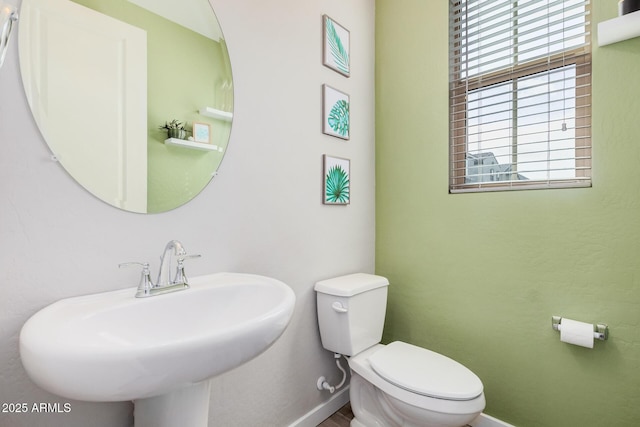 half bathroom featuring a sink, toilet, and baseboards