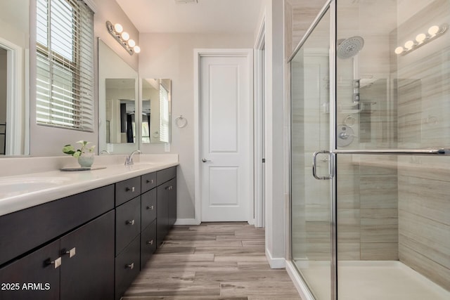 bathroom featuring double vanity, a shower stall, and a sink