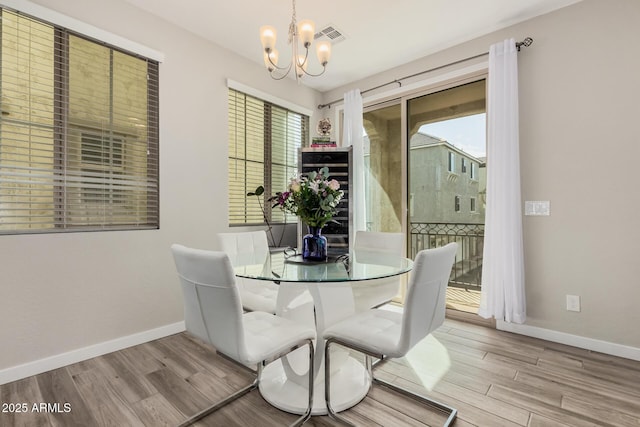 dining area featuring visible vents, baseboards, a notable chandelier, and wood finished floors