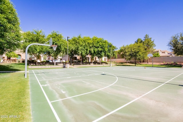 view of basketball court with community basketball court, fence, and a lawn