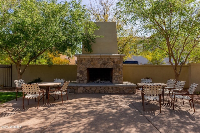 view of patio / terrace featuring fence, an outdoor stone fireplace, and outdoor dining space