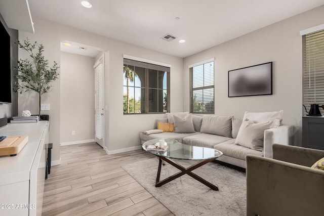 living room featuring baseboards, recessed lighting, visible vents, and light wood-style floors