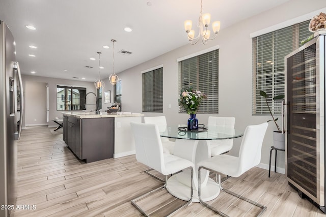 dining space with a chandelier, recessed lighting, beverage cooler, visible vents, and light wood finished floors