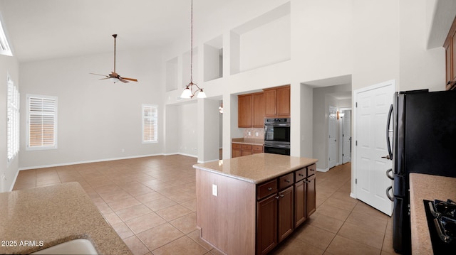 kitchen featuring light tile patterned floors, ceiling fan, a center island, black appliances, and backsplash