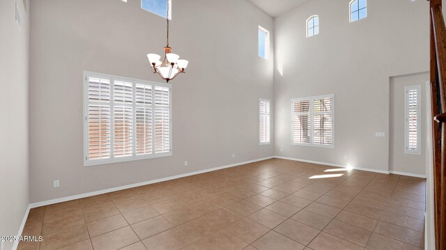 interior space featuring a notable chandelier, a towering ceiling, baseboards, and light tile patterned floors