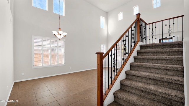 stairway with a chandelier, a high ceiling, tile patterned floors, and baseboards