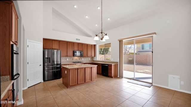 kitchen with decorative backsplash, a center island, stainless steel appliances, light countertops, and light tile patterned flooring