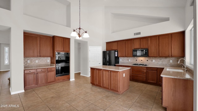 kitchen with black appliances, visible vents, brown cabinets, and a sink
