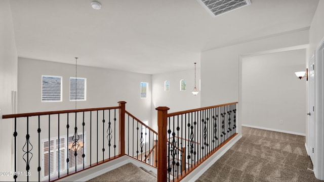 hall featuring an upstairs landing, carpet flooring, visible vents, and baseboards