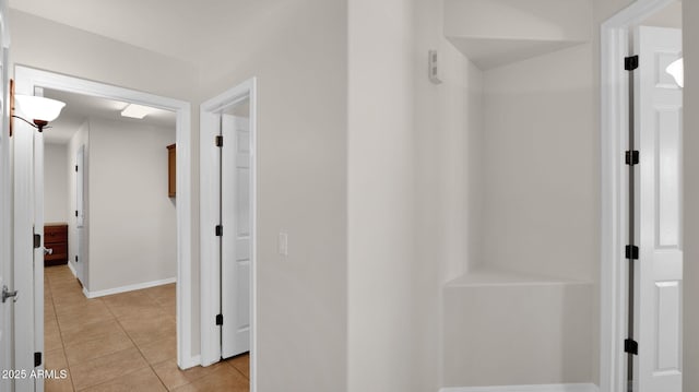 hallway with light tile patterned flooring and baseboards