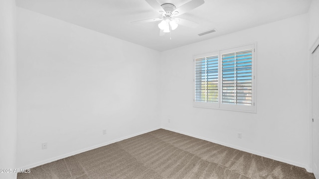 carpeted spare room with baseboards, visible vents, and ceiling fan