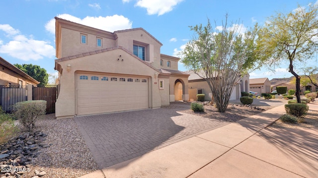 mediterranean / spanish house featuring a garage, decorative driveway, fence, and stucco siding