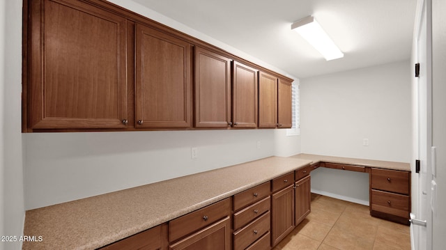 kitchen featuring brown cabinetry, built in study area, and light tile patterned floors