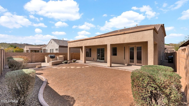 rear view of property with a patio area, a fenced backyard, and stucco siding