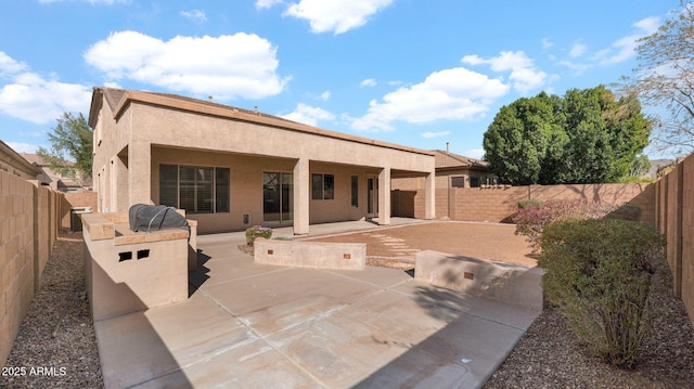 rear view of house featuring stucco siding, a fenced backyard, and a patio