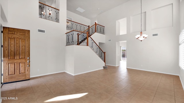 tiled foyer entrance featuring stairway, baseboards, visible vents, and an inviting chandelier