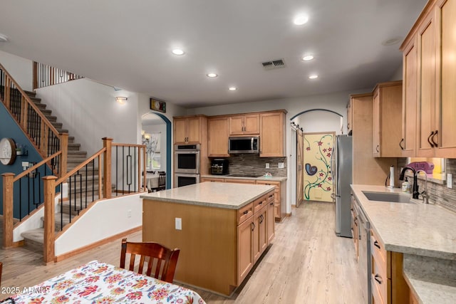 16210 W Durango St, Goodyear, AZ 85338 - kitchen with appliances with stainless steel finishes, arched walkways, decorative backsplash, recessed lighting, and light wood finished floors