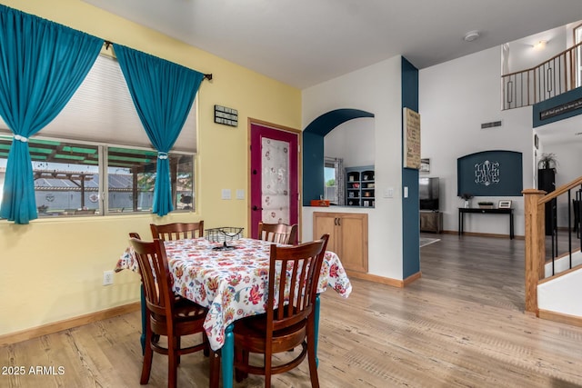 16210 W Durango St, Goodyear, AZ 85338 - dining room featuring light wood finished floors, arched walkways, stairs, a high ceiling, and plenty of natural light