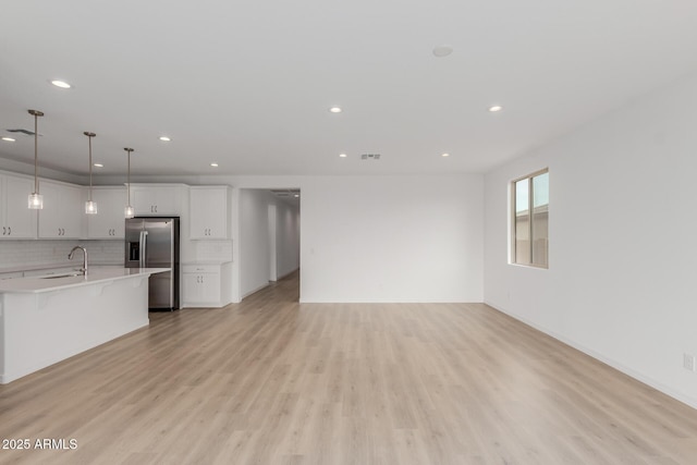 unfurnished living room with sink and light hardwood / wood-style floors