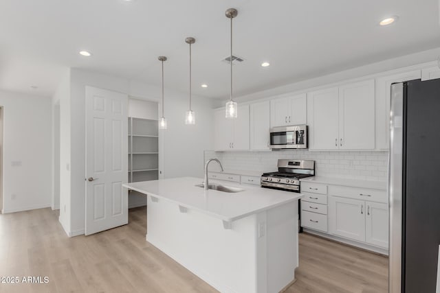 kitchen featuring white cabinetry, sink, pendant lighting, a kitchen island with sink, and appliances with stainless steel finishes