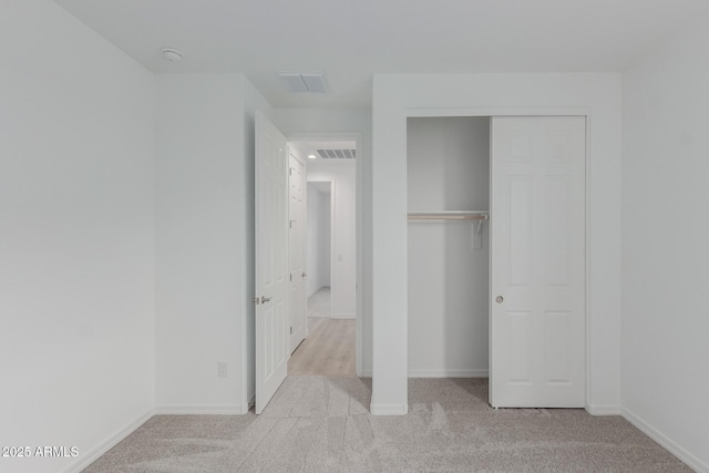 unfurnished bedroom with light colored carpet and a closet