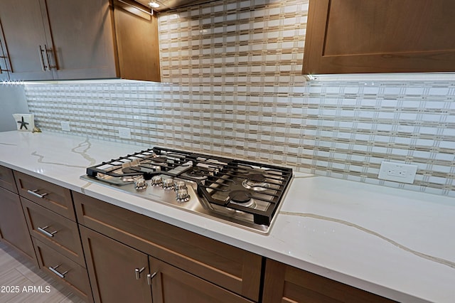 kitchen featuring tasteful backsplash, stainless steel gas stovetop, and light stone countertops