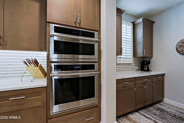 kitchen featuring tasteful backsplash, light stone countertops, and double oven