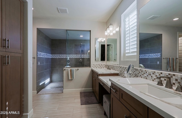 bathroom with tiled shower, vanity, and backsplash