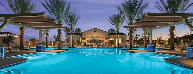 pool at dusk featuring a pergola