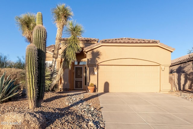 view of front of property featuring an attached garage, a tiled roof, concrete driveway, and stucco siding