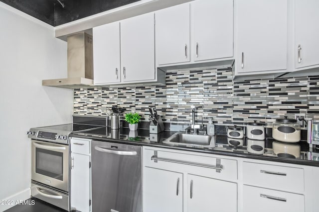 kitchen featuring appliances with stainless steel finishes, dark countertops, white cabinetry, and ventilation hood