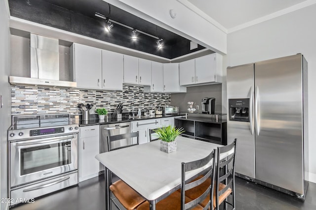 kitchen with stainless steel appliances, white cabinetry, wall chimney range hood, decorative backsplash, and dark countertops