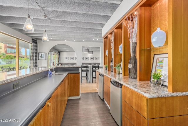 kitchen with refrigerator, brown cabinets, decorative light fixtures, a sink, and modern cabinets