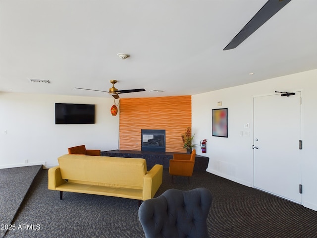 carpeted living area with ceiling fan, a glass covered fireplace, visible vents, and baseboards