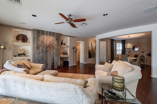 living room featuring built in shelves, dark hardwood / wood-style flooring, and ceiling fan