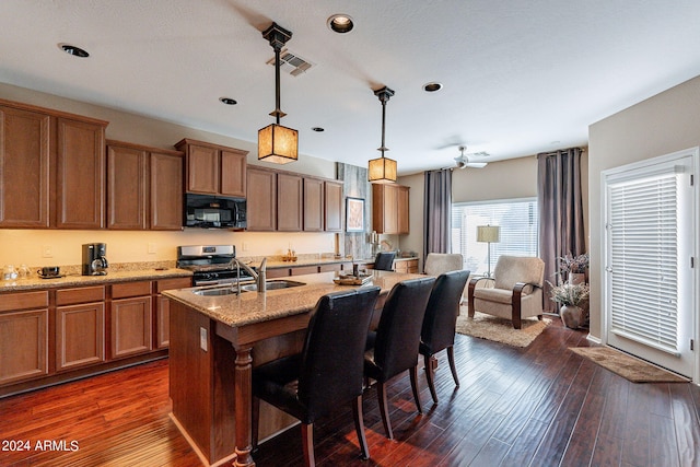 kitchen featuring a kitchen bar, decorative light fixtures, range, sink, and dark hardwood / wood-style flooring