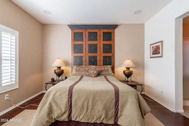 bedroom with multiple windows and dark hardwood / wood-style floors