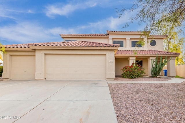 mediterranean / spanish house featuring stucco siding, a tiled roof, concrete driveway, and a garage