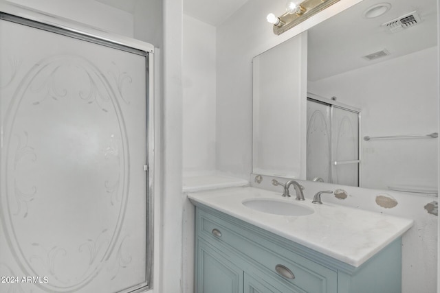 bathroom with a shower with shower door, visible vents, and vanity