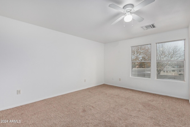 carpeted spare room with visible vents, baseboards, and ceiling fan