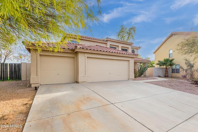 mediterranean / spanish-style home with fence, a tiled roof, concrete driveway, stucco siding, and a garage