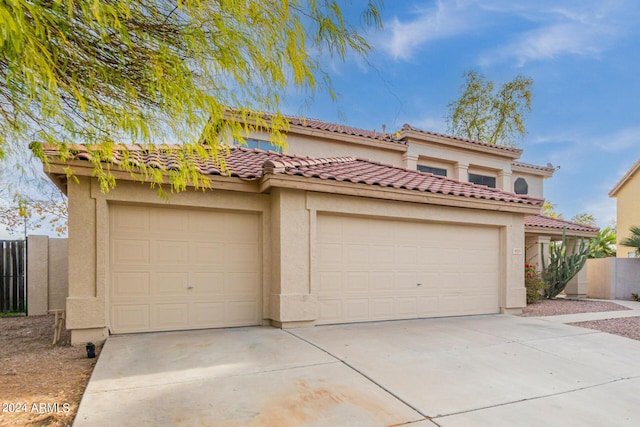 view of front of house featuring concrete driveway, fence, a tile roof, and stucco siding