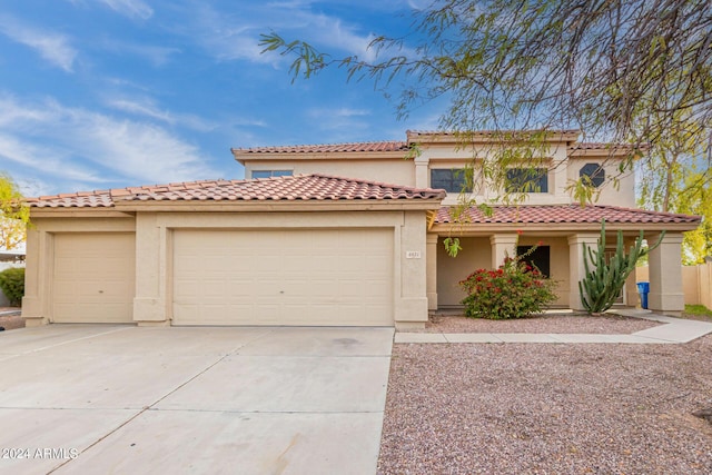 mediterranean / spanish house featuring concrete driveway, a tiled roof, an attached garage, and stucco siding