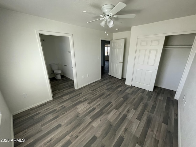 unfurnished bedroom featuring ensuite bathroom, dark wood-type flooring, ceiling fan, and a closet